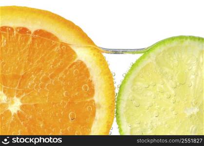 Orange and lime slices in water with air bubbles on white background