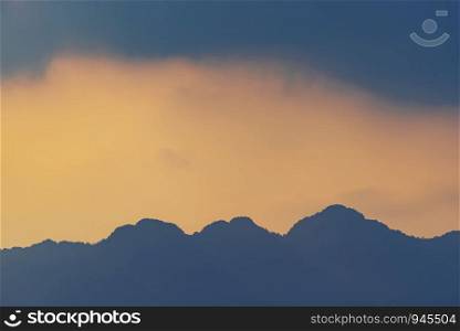 Orange and yellow sunset with mountains silhouettes. Gradient vivid nature background