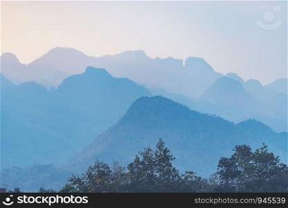 Orange and yellow sunset with mountains silhouettes. Gradient vivid nature background