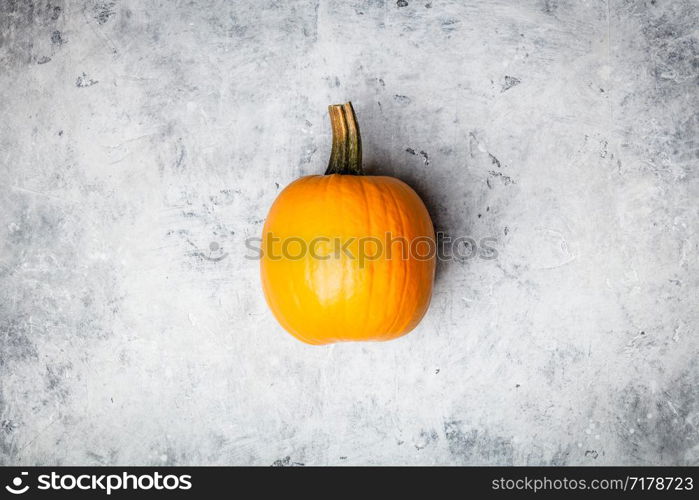 Orange autumn pumpkin on grey concrete background, flat lay. Orange autumn pumpkin on grey concrete background