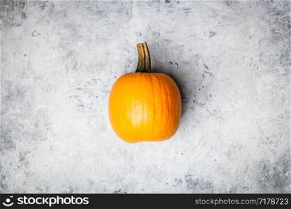 Orange autumn pumpkin on grey concrete background, flat lay. Orange autumn pumpkin on grey concrete background