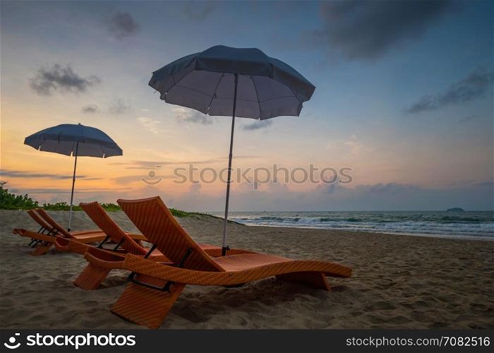 Orange beach chairs and parasols on sandy beach with morning sky and sea