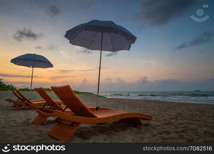 Orange beach chairs and parasols on sandy beach with morning sky and sea