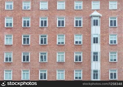 Orange brick wall vintage building. Glass window of skyscraper apartment or hotel building. Exterior brick wall of residential building. Architecture design. Window of building texture background.