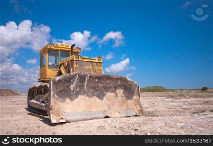 Orange bulldozer after the work is on a background of blue sky