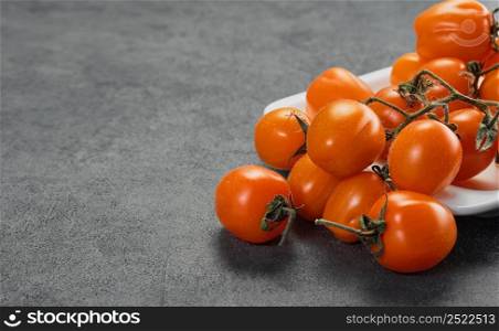 Orange cherry tomatoes on a gray table. Dark style, close-up with copy space. Ingredients for salad or vegetable dishes