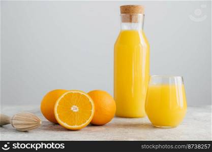 Orange citrus juice in glass bottle, fresh oranges and squeezer near isolated on white background. Selective focus. Copy space for text