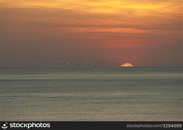 Orange clouded sunset over the calm ocean horizon