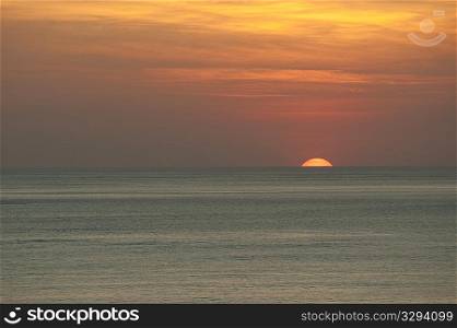 Orange clouded sunset over the calm ocean horizon