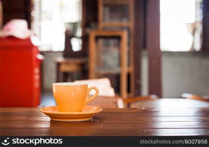 Orange coffee cup on wooden table in coffee shop