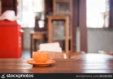 Orange coffee cup on wooden table in coffee shop