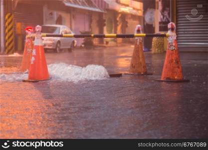 Orange cones around overflowing manhole during typhoon