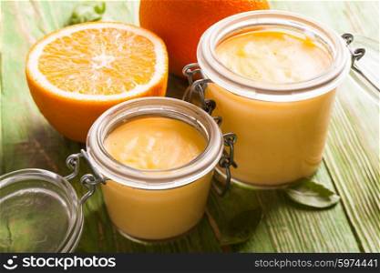 Orange curd in glass jars on the table. Orange curd