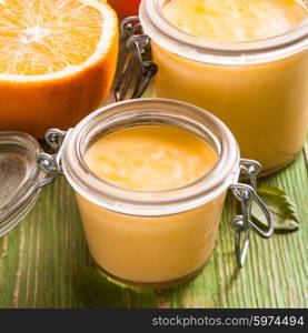Orange curd in glass jars on the table. Orange curd
