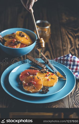 Orange dessert with wine honey or maple syrup and ginger spice, decorated pomegranate berries. Wonderfully sweet, rich and fresh food. Dark rustic background, copy space for you text.