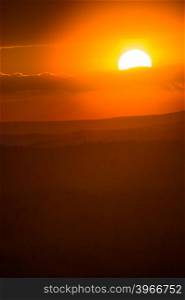 orange disc of the sun sinks to the horizon at sunset