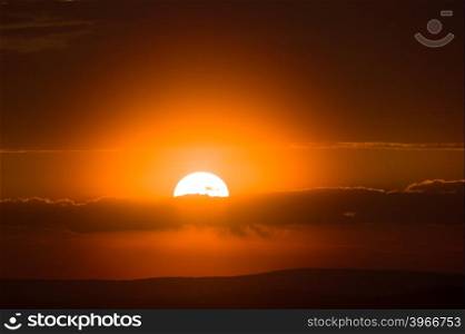 orange disc of the sun sinks to the horizon at sunset