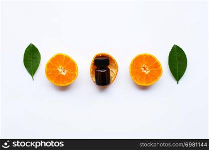 Orange essential oil with fresh orange citrus fruits and green leaves on white background.