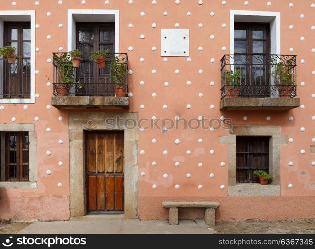 Orange Facade of old house with windows and wooden door. CA?ceres, Spain.