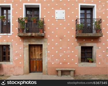 Orange Facade of old house with windows and wooden door. CA?ceres, Spain.