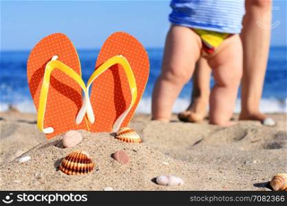 Orange flip-flops in sand on the beach in Barcelona.
