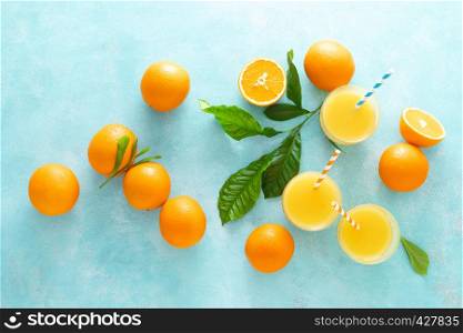 Orange freshly squeezed juice in glass and fresh fruits on a blue vivid background, top view