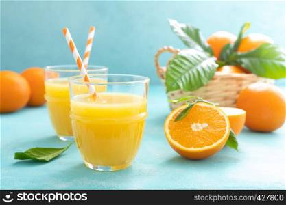 Orange freshly squeezed juice in glass and fresh fruits on a blue vivid background