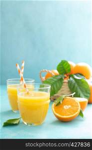 Orange freshly squeezed juice in glass and fresh fruits on a blue vivid background