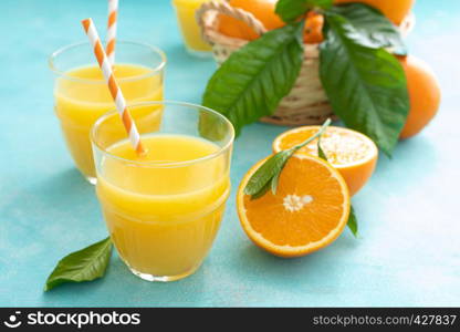 Orange freshly squeezed juice in glass and fresh fruits on a blue vivid background