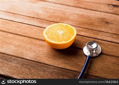 Orange fruit and Doctor stethoscope on wooden table, Vitamin C, Healthy lifestyle diet food concept