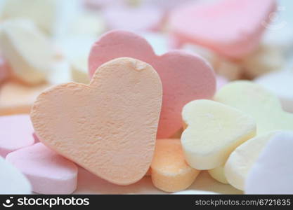 orange fruit candy heart on a pile of candy hearts
