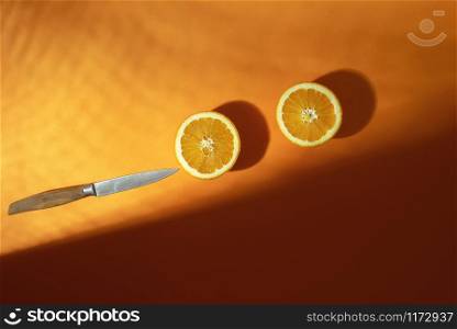 Orange fruit cut in half on a lush lava paper background, in sunlight with shadows. Above view of fresh oranges, sliced in two. Summer tropical fruits
