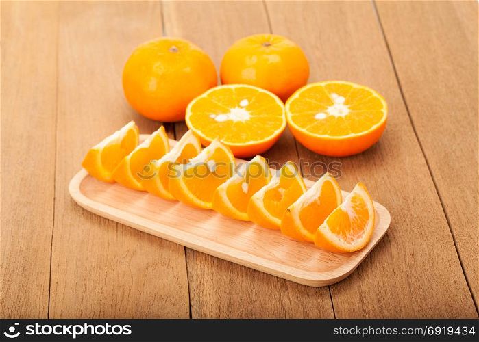 orange fruit in wooden plate on wood background