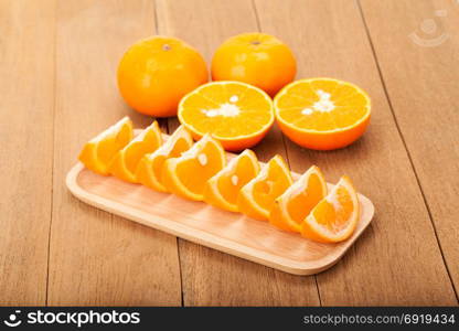 orange fruit in wooden plate on wood background