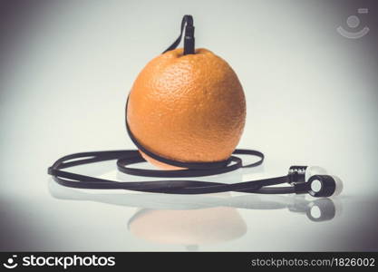 Orange fruit music player: headphones coming from of orange fruit on a white background.
