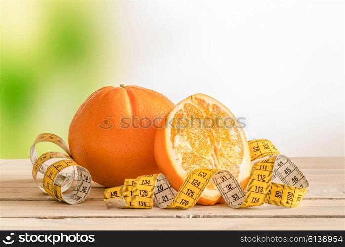 Orange fruit with a yellow measure tape on a wooden table