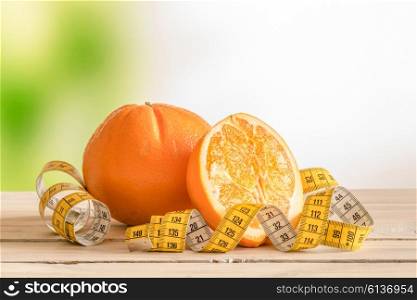 Orange fruit with a yellow measure tape on a wooden table