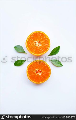 Orange fruits and green leaves on a white background. Top view