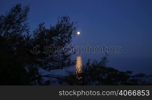 Orange full moon rising over the Sea. Moonlight reflection on the water. Beautiful nightscape near the coast.
