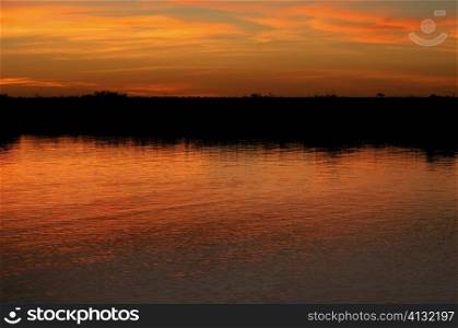 Orange glow of the sky in water at sunset, Okavango Delta, Botswana