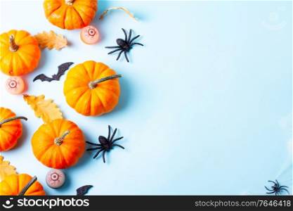 Orange halloween pumpkins wuth spiders on blue background flat lay border with copy space. Halloween flat lay background