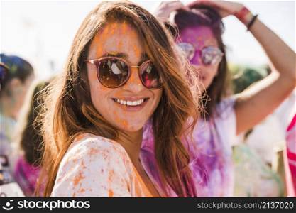 orange holi color woman s face wearing sunglasses