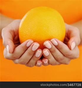 orange in woman hands close up
