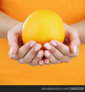 orange in woman hands close up