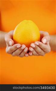 orange in woman hands close up