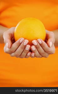 orange in woman hands close up