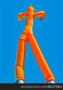 Orange inflatable man on blue sky background. Orange inflatable man