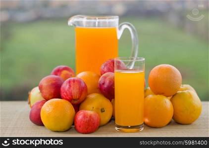 orange juice and lots of fruits on wooden table outdoor