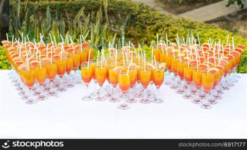 Orange juice cocktail in a flute glasses and slice of fresh orange with draw on white table,Party outdoor.