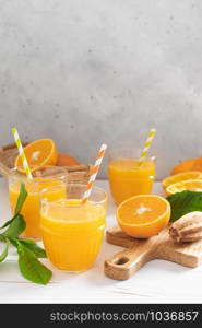 Orange juice. Freshly squeezed juice in glasses and fresh fruits with leaves